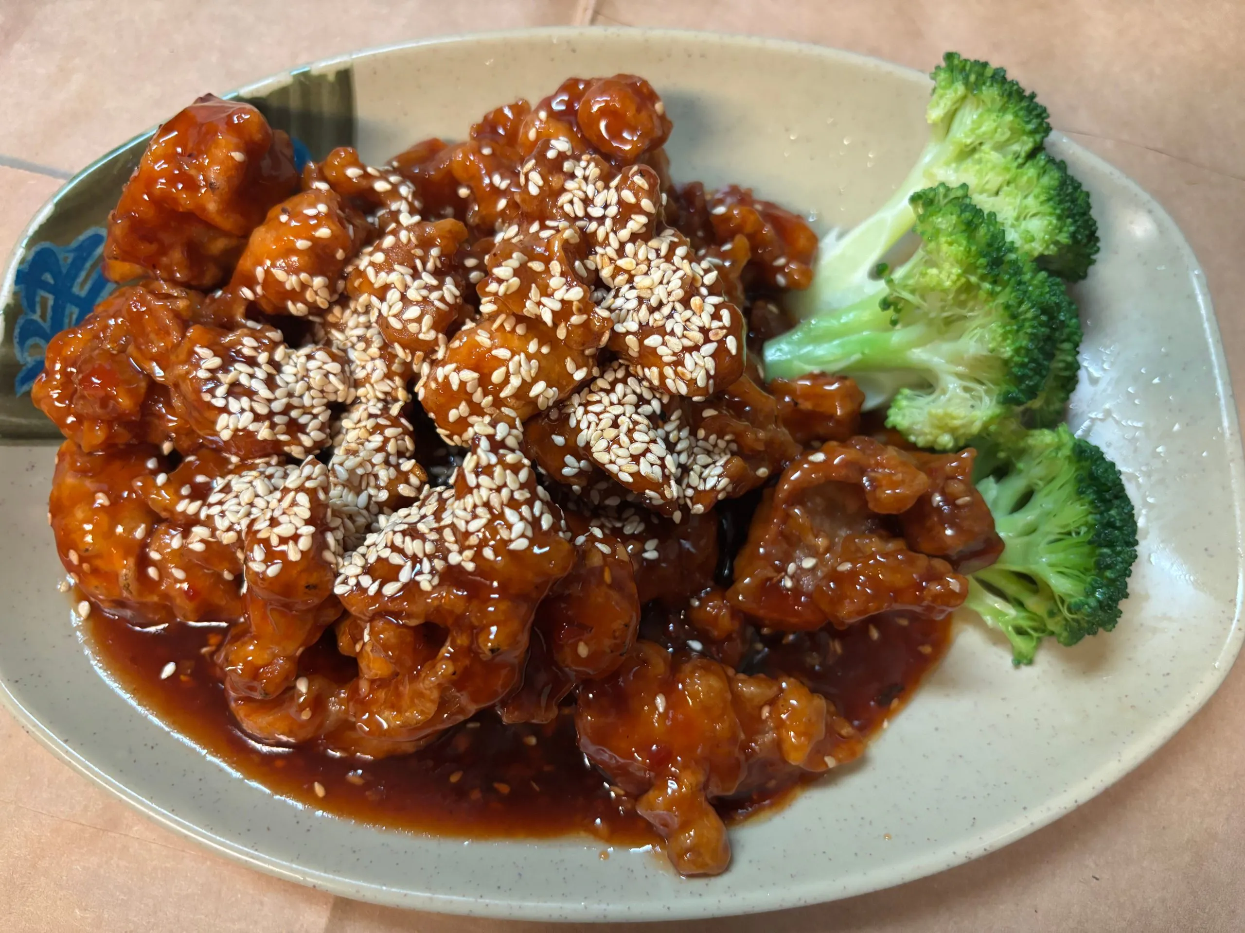 Sesame glazed sweet chicken served with fresh broccoli florets at The Wok, an Asian Fusion Restaurant in Rochester